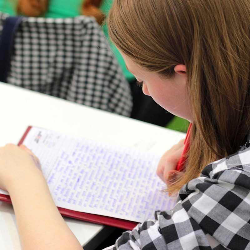 Student writing essay in classroom setting